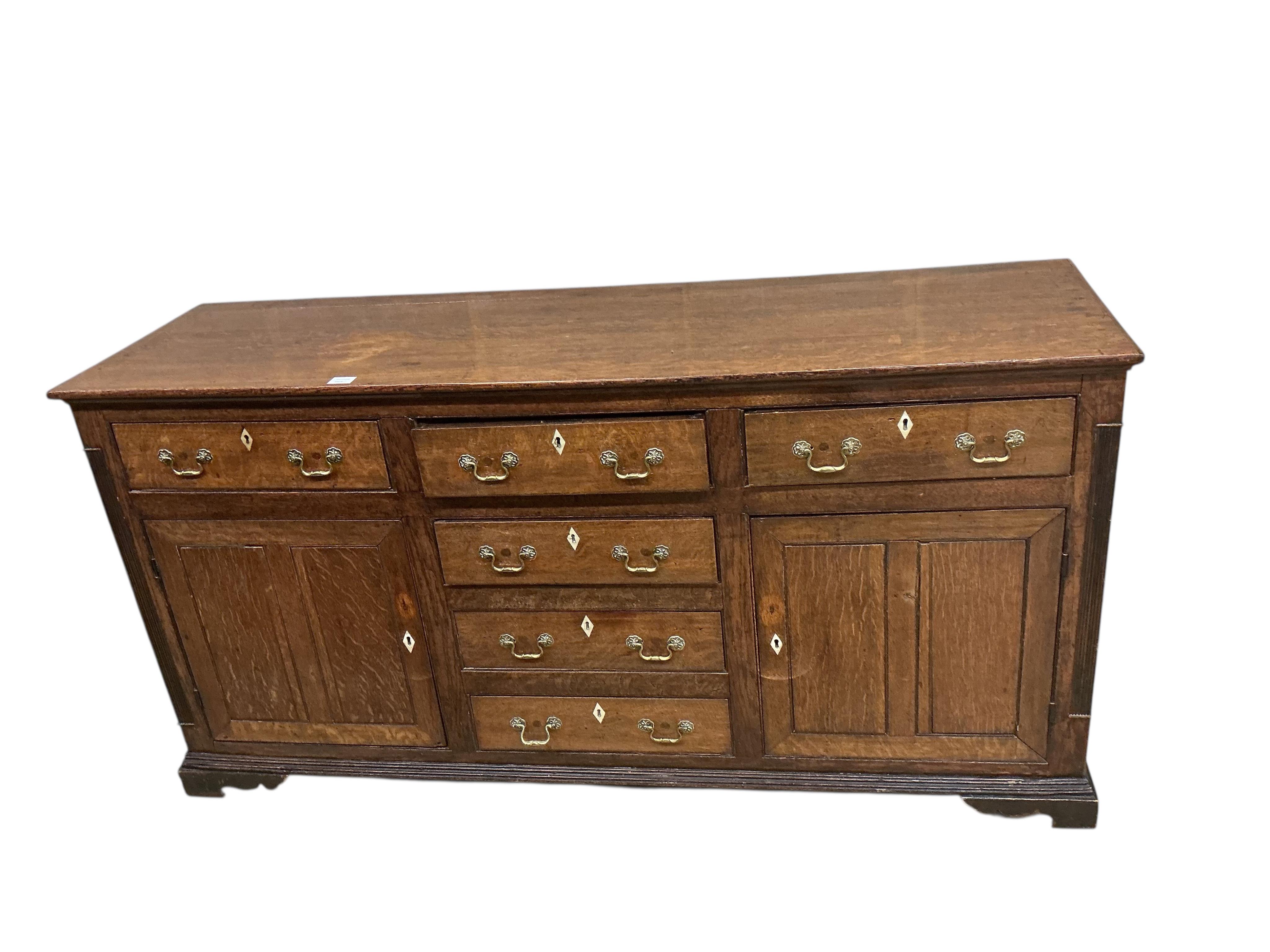 A George III oak low dresser base, later replacement handles, width 178cm, depth 54cm, height 91cm